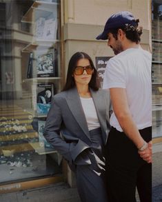 a man and woman standing in front of a store window with their hands on each other's hips