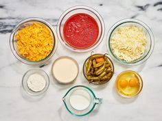 an assortment of ingredients in bowls on a marble counter top, including eggs, cheese and other foodstuffs