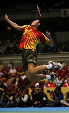 a man jumping in the air while holding a tennis racquet on top of a court