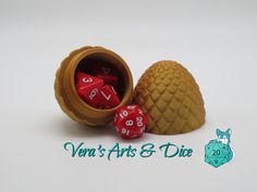 two red dices sitting in a wooden container next to a pine cone with the word vein's arts & diff written on it