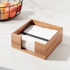 two napkins in a wooden holder next to apples