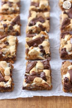 chocolate and marshmallow squares are arranged in rows on a piece of parchment paper