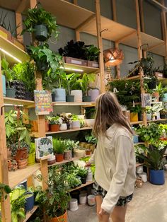 a woman is looking at potted plants on shelves