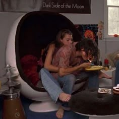 two people sitting in a podoon shaped chair with food on the plate and one person holding a lit candle