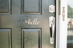 a green door with the word hello written on it and an open front door handle