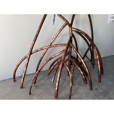 a sculpture made out of branches on the floor in front of a wall with a light