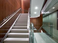 an empty staircase with glass handrails and wood paneling on the wall behind it