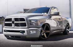 a silver ram truck parked in front of a garage door with it's hood up