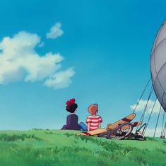 two people sitting on the grass looking at an object in the sky with a balloon attached to it