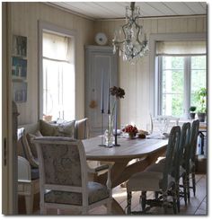 a dining room table with chairs and a chandelier hanging from it's ceiling