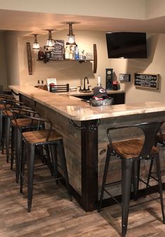 a bar with several stools in front of it and a flat screen tv on the wall