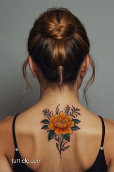 a woman with a flower tattoo on her back neck and behind the neck is an orange rose