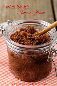 a glass jar filled with food sitting on top of a checkered table cloth next to a wooden spoon