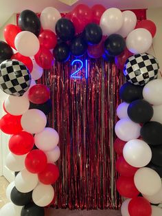 a red, white and black balloon arch with checkered balloons