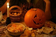 a pumpkin sitting on top of a table next to a bowl of food and a candle