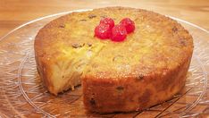 a cake with two pieces missing from it on a glass platter and wooden table