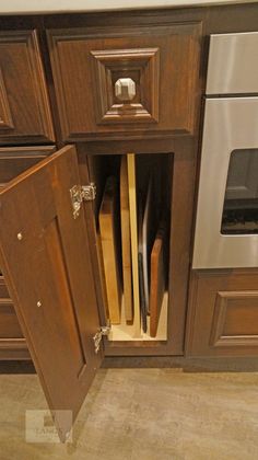 an open cabinet in the middle of a kitchen with wooden doors and drawers on both sides