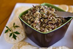 a bowl filled with food next to tortilla chips on a white and green plate