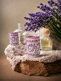 lavender flowers are sitting on a table next to two jars with perfumes in them