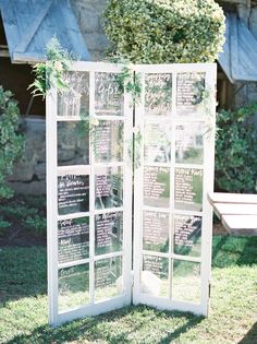 an old window is decorated with greenery and seating cards