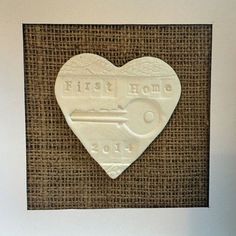 a white heart shaped plaque with the words south plain on it in front of a burlap background