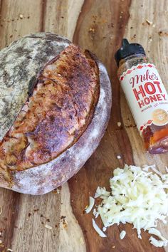 a loaf of bread sitting on top of a wooden table next to a bottle of hot honey