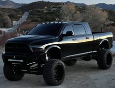 a large black truck parked on top of a dirt field