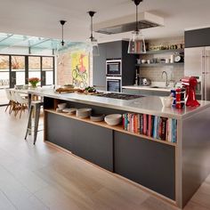 an open kitchen with stainless steel appliances and lots of books on the counter top in front of it