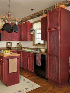 a kitchen with red cabinets and an island in front of the stove top oven is decorated with pots and pans