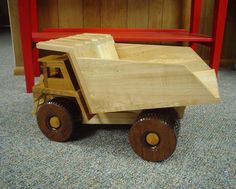 a wooden toy truck sitting on top of a carpeted floor next to a red bench