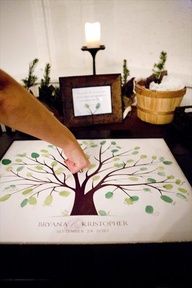 a person is pointing at a wedding guest book on a table with candles in the background