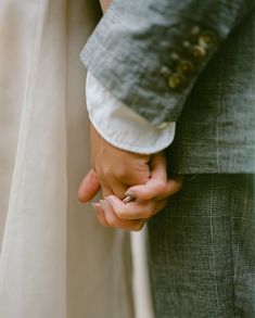 a close up of two people holding each other's hands while wearing wedding rings