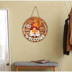 a welcome sign hangs on the wall next to a bench and coat rack in a room