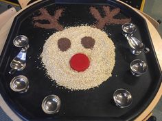 a reindeer made out of sand on top of a black tray with silver spoons