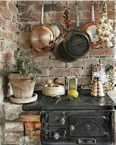 an old stove with pots and pans hanging on the wall