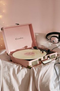 a record player sitting on top of a bed next to headphones and an mp3 player