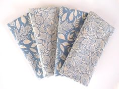 four napkins with blue and gold designs on them sitting next to each other in front of a white background