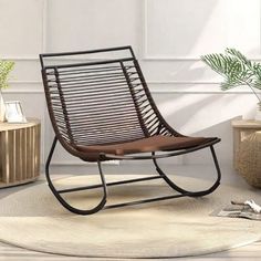 a brown rocking chair sitting on top of a rug next to a potted plant