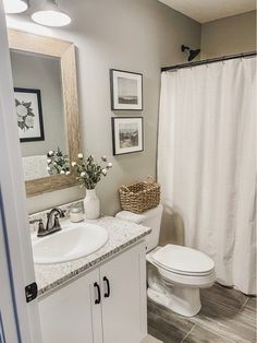 a bathroom with a white shower curtain next to a toilet and sink in front of a mirror