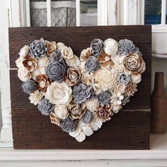 a heart made out of paper flowers sitting on top of a wooden box in front of a window