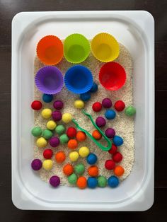 a white tray filled with different colored cupcake liners and pom - poms