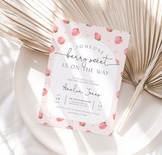 a white plate topped with a card next to an open palm leaf and paper fan