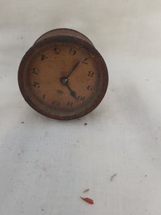 an old clock sitting on top of a white cloth covered table next to a wall