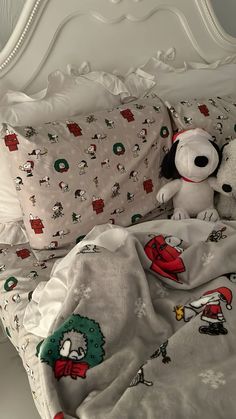 two stuffed animals sitting on top of a bed covered in sheets and blankets with cartoon characters