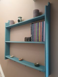 two blue shelves with books and vases on them in the corner of a room