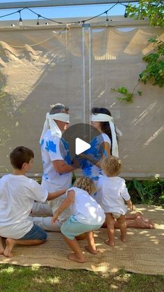 a group of people standing around each other in front of a screen with trees and grass