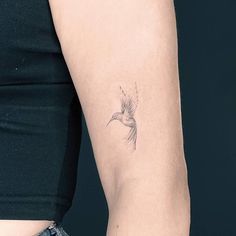 a woman's arm with a small bird tattoo on the left side of her arm