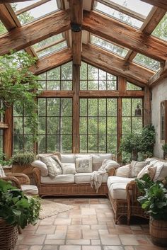 a living room filled with lots of furniture and windows covered in wooden beams, surrounded by greenery