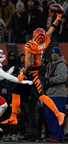 a football player jumping up into the air with a ball in his hand and people watching