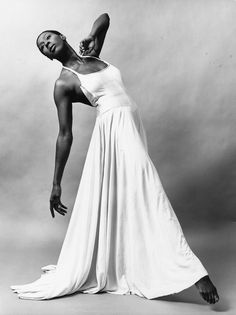 a black and white photo of a woman in a long dress with her arms stretched out